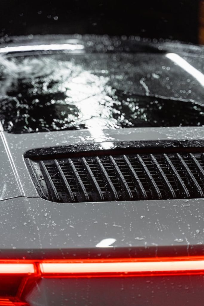 Close-up view of a luxury sports car with rain droplets on the surface, showcasing sleek design.